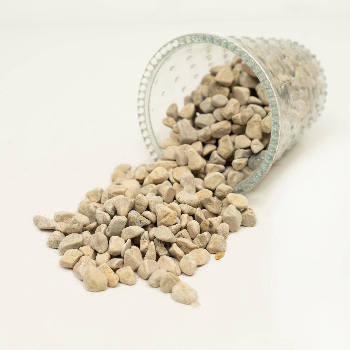 The Spotted Donkey natural white river rock pebbles spilling out of a decorative glass vase for home decor
