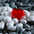 The Spotted Donkey white river rock pebbles surrounding a smooth red glass heart for decorative display.