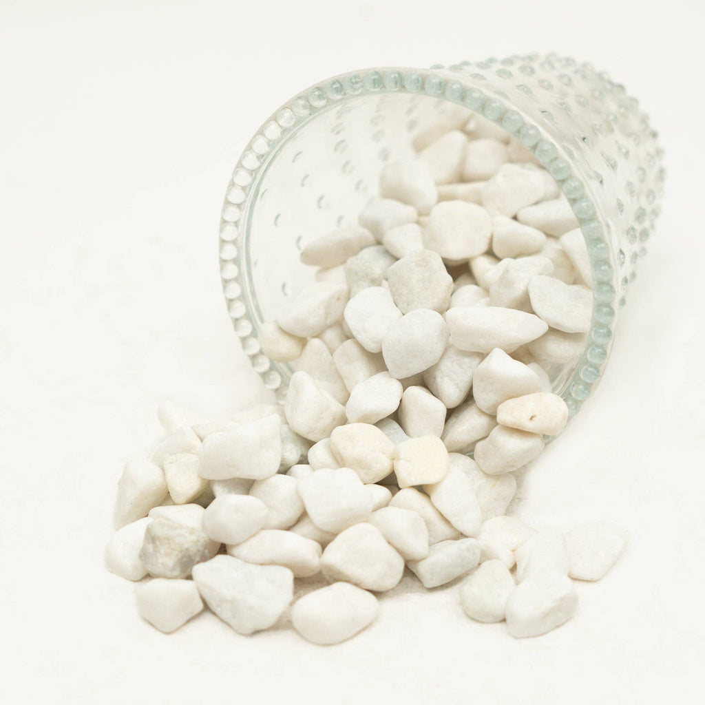 The Spotted Donkey white river rock pebbles spilling from a clear glass container for decorative potting and display.
