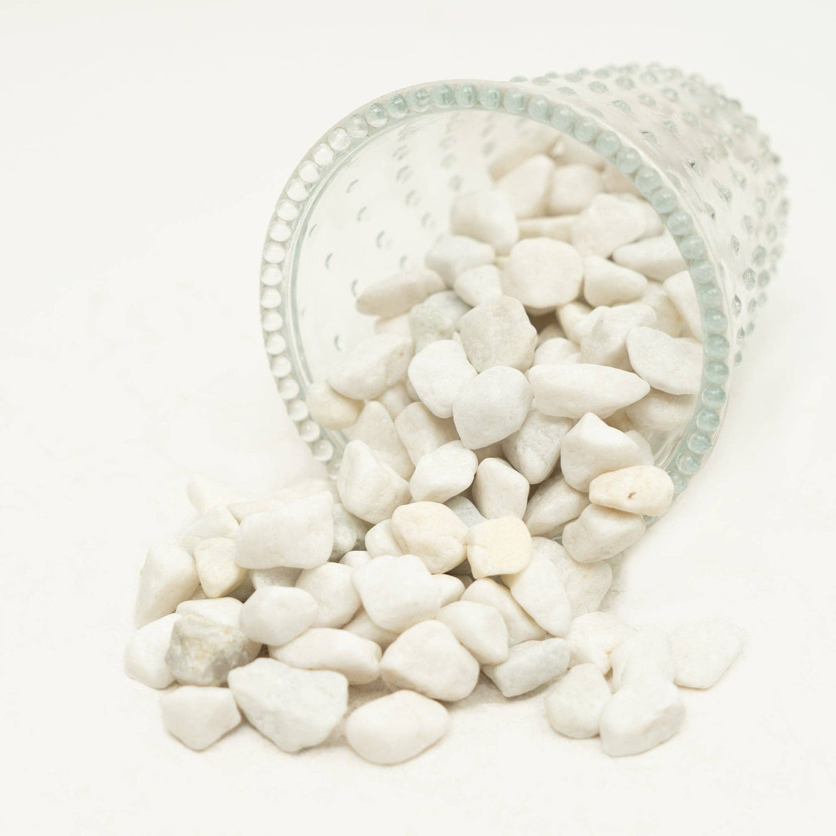 The Spotted Donkey white river rock pebbles spilling from a clear glass container for decorative potting and display.